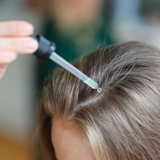 Pipette påfører hårserum i hovedbunden langs skilningen i håret.